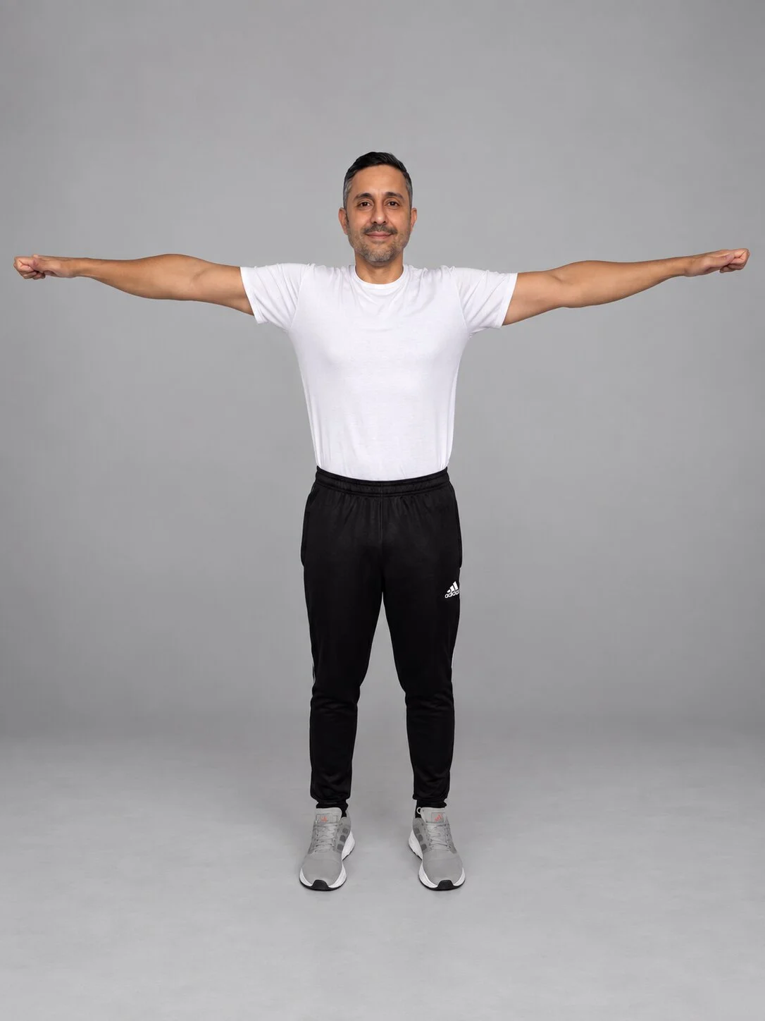 Hombre de pie con los brazos extendidos, ejercicio de alineación postural